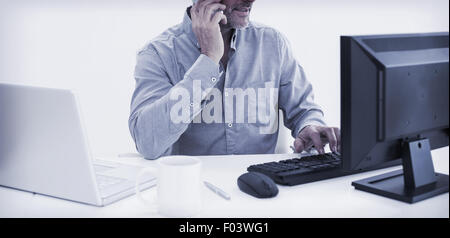 Businessman with cellphone, laptop and computer at desk Stock Photo