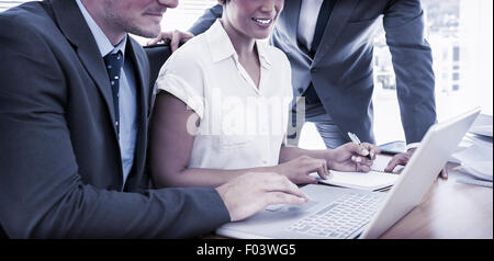 Young colleagues using laptop at office desk Stock Photo