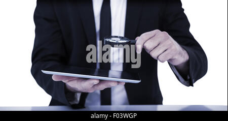 Businessman looking at his tablet through magnifying glass Stock Photo