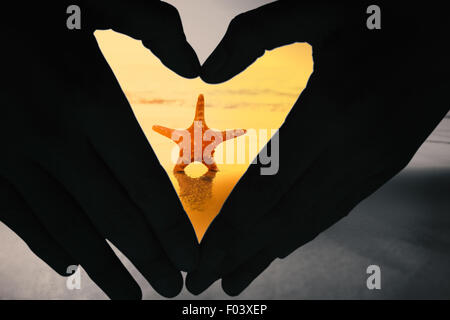 Composite image of woman making heart shape with hands Stock Photo