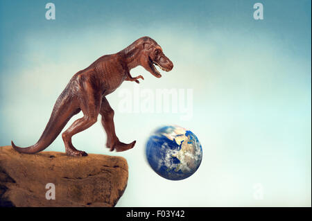 extinction or sustainability concept dinosaur kicking the planet earth off a precipice Stock Photo