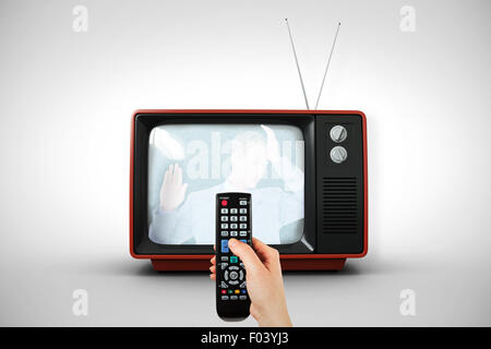 Composite image of hand holding remote control Stock Photo