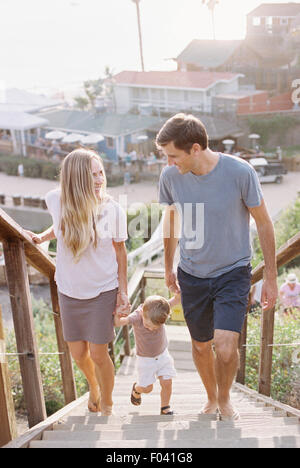 Couple holding hands with their young son, walking up a staircase.