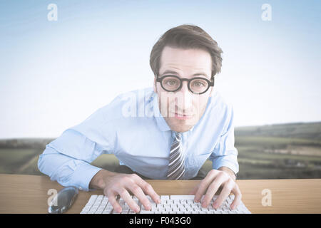 Composite image of businessman typing on his keyboard wearing glasses Stock Photo