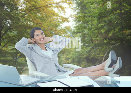 Composite image of businesswoman relaxing in a swivel chair Stock Photo