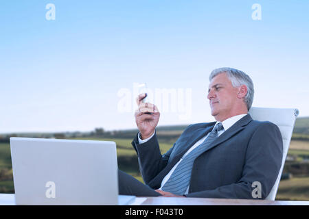 Composite image of businessman using his smartphone Stock Photo