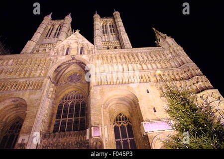 A Christmas tree outside the main entrance of an illuminated Lincoln Cathedral during the City's Christmas market, England UK Stock Photo