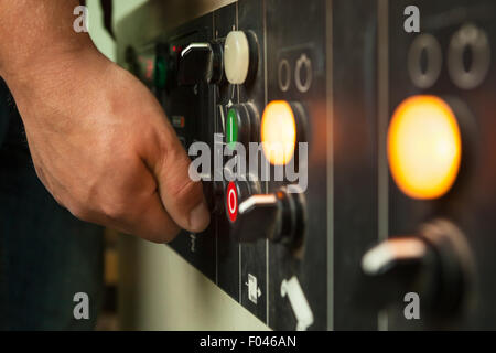 Male hand operating switches and buttons on control panel. Stock Photo