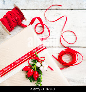 simple gift wrapped with brown paper and decorated with red ribbon and berries Stock Photo