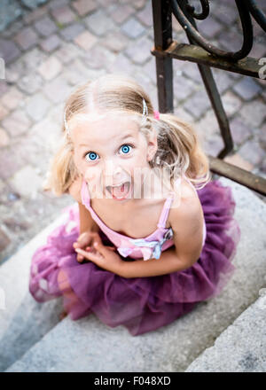 Little blond girl looking at the camera and shouting. Top view Stock Photo