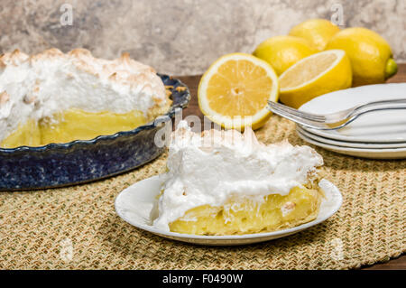 Slice of lemon meringue pie on white serving plate Stock Photo