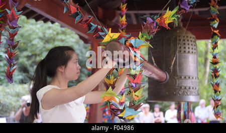 Berlin, Germany. 6th Aug, 2015. Mai Linh rings the Friedensglocke (peace bell) during a remembrance event on the 70th anniversary of the atomic bombing of Hiroshima and Nagasaki, in Volkspark Friedrichshain park in Berlin, Germany, 6 August 2015. PHOTO: RAINER JENSEN/DPA/Alamy Live News Stock Photo