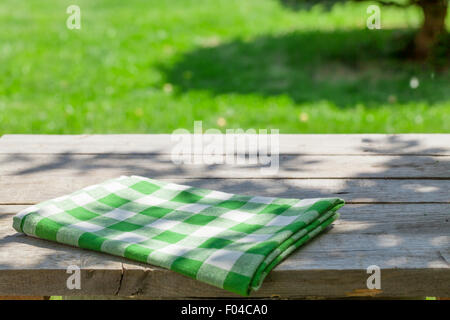 Empty wooden garden table with tablecloth with green bokeh background Stock Photo