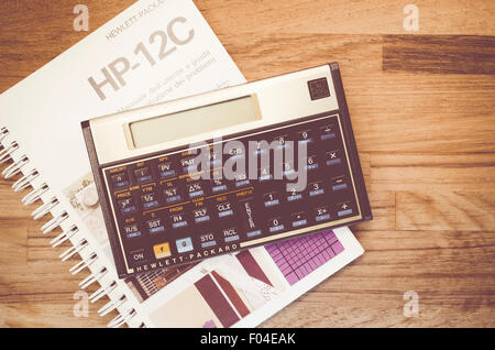 HP-12C Hewlett-Packard rpn financial calculator and manual on a natural wood table top background Stock Photo