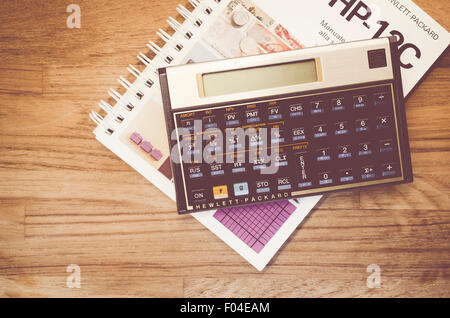 HP-12C Hewlett-Packard rpn financial calculator and manual on a natural wood table top background Stock Photo