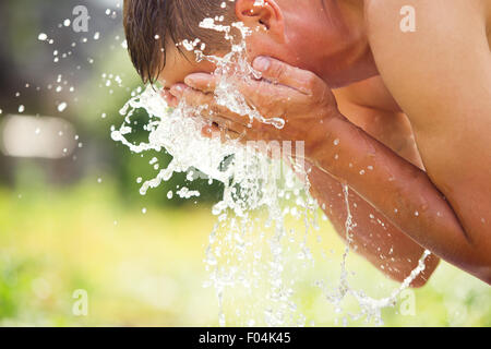 A man refreshes himself with a splash of cool, fresh water on his face. Stock Photo