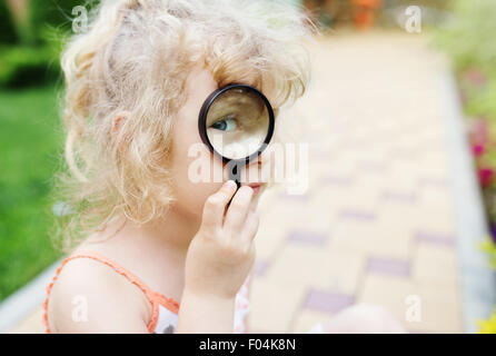 Little girl looking through a magnifying glass Stock Photo