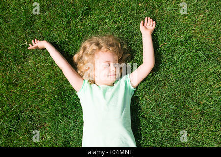 Dreaming adorable girl lying on grass, top view Stock Photo
