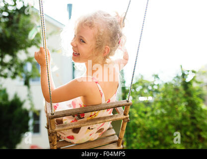 Happy girl having fun on a swing on summer day Stock Photo