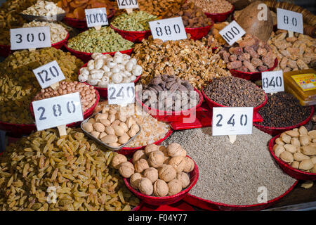 Dates, walnuts, raisins, cloves, caraway seeds, black pepper and cardamon are displayed in bowls in the Old Delhi spice market Stock Photo