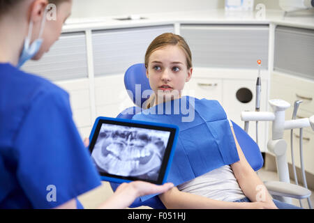 dentist showing x-ray on tablet pc to patient girl Stock Photo