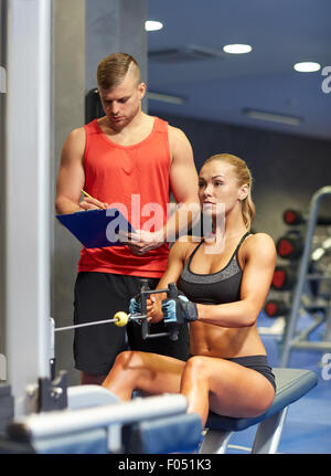 man and woman flexing muscles on gym machine Stock Photo