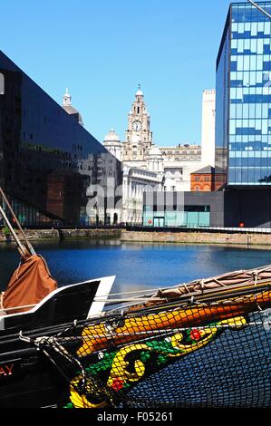 The Liver building and office blocks seen from Canning Dock with the front of a sailing ship in the foreground, Liverpool, UK. Stock Photo