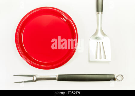 A set of barbeque tools and plastic plates placed on a white surface symbolizing barbeque time. Stock Photo