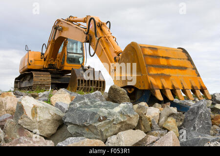 yellow excavator on top of big heap of stones, close up Stock Photo
