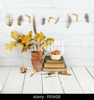 autumn decorations at home - feather and seedheads garland, oak leaves, crab apples, nuts, books Stock Photo