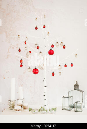 Christmas decorations at home - birch Christmas tree, candles, lanterns, silver and red mercury glass baubles, tealights, Stock Photo