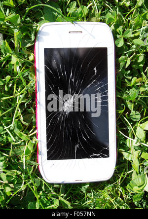 Smartphone with broken screen lying on the grass Stock Photo