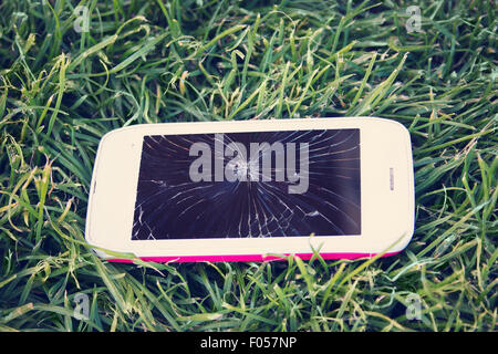 Smartphone with broken screen lying on the grass Stock Photo