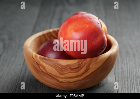 nectarines in olive wood bowl on oak table Stock Photo