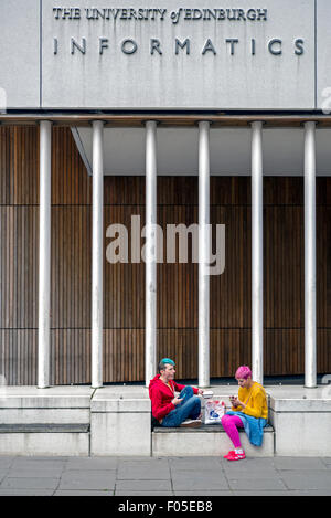 Two brightly coloured students sitting outside the University of Edinburgh's School of Informatics building. Stock Photo