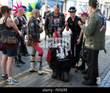 Police woman with a group punk rockers; rebel rebelling rebellion Blackpool festival spike spiked spiky mohican mohawk hair hairstyle outlaw steampunk doc martens rock rocker music event Stock Photo