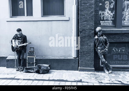 Busker and statue of John Lennon in Liverpool Stock Photo