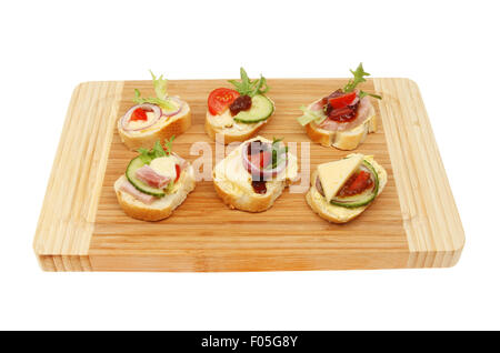 Selection on canapes on a wooden board isolated against white Stock Photo