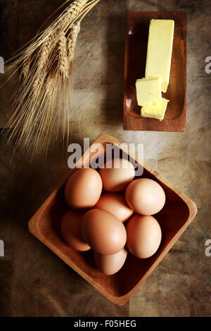 Eggs with butter and wheat on rustic wooden table Stock Photo