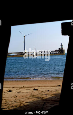 Blue Yacht passing wind turbine, Blyth Harbour, Northumberland Stock Photo