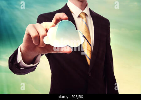 Businessman holding a cloud computing icon over cloudscape background Stock Photo