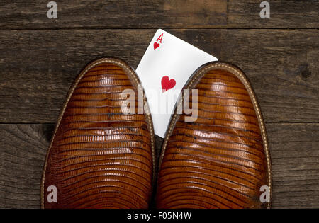 Poker player with cheating hand under cowboy boot. Stock Photo