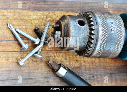 Macro shot of an old drill head and screws over a wooden table Stock Photo