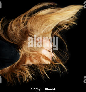 Young attractive woman with long blonde flying hair at night Stock Photo
