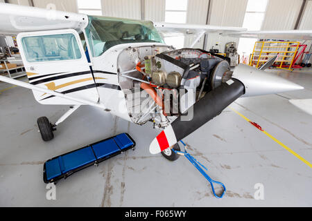 Small two-seated propeller airplane is being repaired in a hangar at the airport. Stock Photo