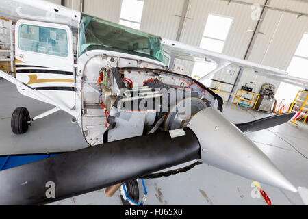 Small two-seated propeller airplane is being repaired in a hangar at the airport. Stock Photo