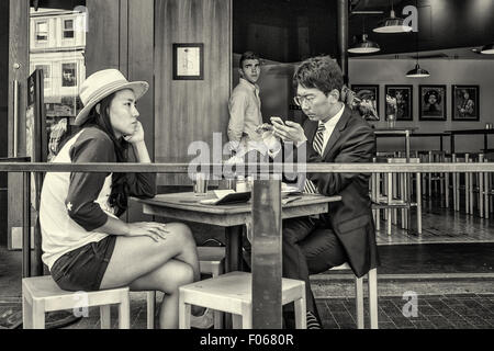 A couple sitting at a table in an outdoor cafe' using their mobile phones Stock Photo