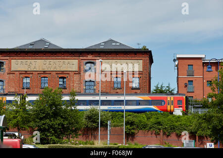 Local dmu passenger train at Warrington central passing old warehouses Stock Photo
