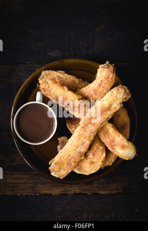 Homemade churros and hot chocolate in the plate from above on wooden background Stock Photo