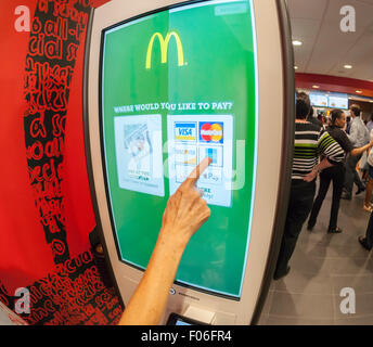 A diner chooses her payment method at a 'Create Your Taste' kiosk at a McDonald's in New York on Tuesday, August 4, 2015. The interactive iPad-like digital displays allow customers to customize their order with toppings, new sauces, etc. and have them delivered to their table in a few minutes. McDonald's, which has seen same-store sales drop over three years, is using the kiosks to compete with fast casual restaurants such as Chipotle, Fatburger and a host of others. (© Richard B. Levine) Stock Photo